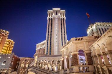 LAS VEGAS, 21 AĞUSTOS 2024: Las Vegas Bulvarı 'nda geceleri yanan Venedik Resort Kulesi ve yaya köprüsünün alçak açılı fotoğrafı. Venedik, Venedik temalı bir kumarhane ve otel..