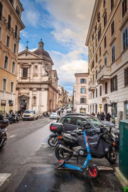 BELGRAD, SERBIA - 15 Mart 2025: Dott elektrikli scooter, otomobil olarak Via dei Serpenti 'ye yaslanıyor ve Santa Maria ai Monti' nin Barok Kubbesi, Roma 'nın orta kesimindeki Monti semtinde bir caddeyi canlandırıyor.