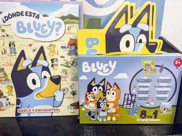 VALENCIA, İSPA - 15 Nisan 2025: Avustralyalı karikatür mavisi dümeni Bluey ile İspanyolca kitap ve kitler, Valencia 'da bir dükkan vitrini dolduruyor, lisanslı çocuk mallarını resmediyor..