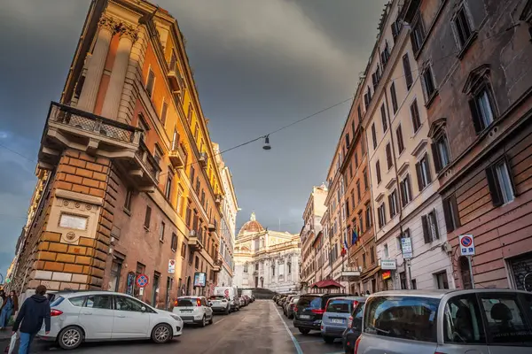 ROME, ITALY - 15 HAZİRAN 2025: Roma Monti bölgesindeki Via Panisperna boyunca görünüm: uzun kollu cepheler, park edilmiş arabalar ve dramatik akşam bulutları altında Santa Maria Maggiore uzak kubbesi.