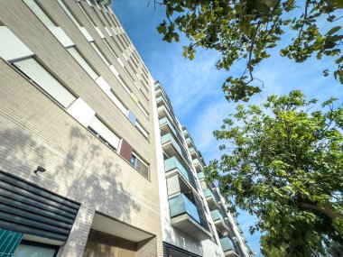 1980 'lerin yüksek tuğlalı apartman bloğu Valencia, İspanya' da, parlak mavi gökyüzüne karşı sıra sıra patenli panjurlar ve cam balkonlar, perspektif yerel emlak yoğunluğunu vurgular.