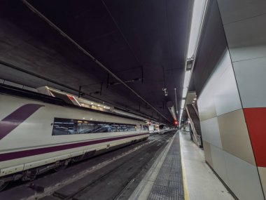 BARCELONA, SPAIN - 12 Nisan 2025: Siemens Velaro tarafından inşa edilen AVE yüksek hız trenleri İspanya 'nın RENFE demiryolu ağının bir parçası olan Barcelona Sants istasyonunun yeraltı koridorunda karşıt hatlarda beklemektedir..