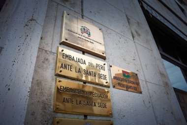 VATİKAN - 15 Ocak 2025: Dominik Cumhuriyeti, Peru, Ekvador 'un Vatikan' daki Kutsal Makam 'ın yanındaki bir duvarda Latin Amerika diplomatik varlığını gösteren diplomatik misyonların işaretleri.