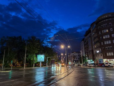 BELGRAD, SERBIA - 22 Nisan 2025: Vozdovac 'taki Ulica Vojvode Stepe' deki Trosarina kavşağından geçen bir tramvay ve arabalara ait gece sahnesi.