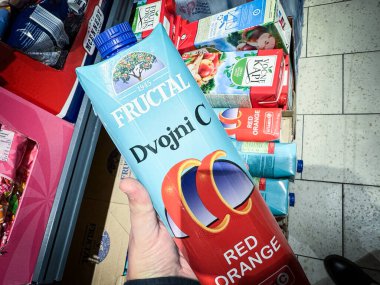 BELGRAD, SERBIA - 22 Nisan 2025: Belgrad 'daki bir süpermarkette el ele tutulan Fructal Dvojni C kırmızı portakal suyu kartonunun yakın çekimi, Fructal, Sloven meyve suyu markasıdır..