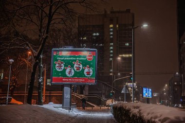 BELGRAD, SERBIA - 22 Aralık 2024: Kar, Coca-Cola 'nın gece yarısı Belgrad şehir merkezinde yakılan festival panosunun etrafına düşer..