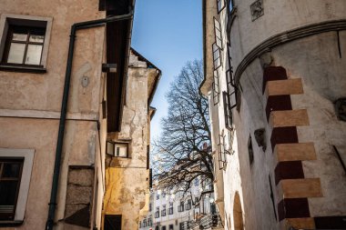 SKOFJA LOKA, SLOVENIA - 17 Aralık 2024: Skofja Loka 'da dar bir sokak kaba sıva duvarlar, açık kereste pencereler, Slovenya' nın ortaçağ merkezindeki tarihi konutlara doğru yapraksız bir ağaç çerçevesi.