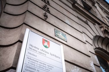 LJUBLJANA, SLOVENIA - 17 Aralık 2024: Ljubljana Belediye Binası Adamic Lundrovo nabrezje 2 ön cephesi, Mestna obcina Ljubljana imzalı belediye arması ve yönetim dizini.