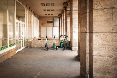 Budapeşte 'nin Keleti İstasyonu yakınlarındaki taştan bir atari salonunun altında üç donanımsız e-scooter duruyor. Uygulama tabanlı mikrohareketlilik filolarının gelişmekte olan taşıma karışımının bir parçası olarak gelişen kaldırım parkına nasıl güvendiğini gösteriyor..
