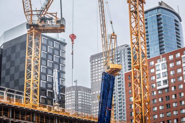 Kule vinçleri, Montreal şehir merkezindeki yeni bir gökdelen inşaatında ağır bölümleri kaldırırken, mevcut apartman kuleleri de sahneyi çerçevelemekte, hızlı ufuk çizgisi büyümesi ve Kanada 'nın yoğun inşaat iklimini yakalamaktadır..