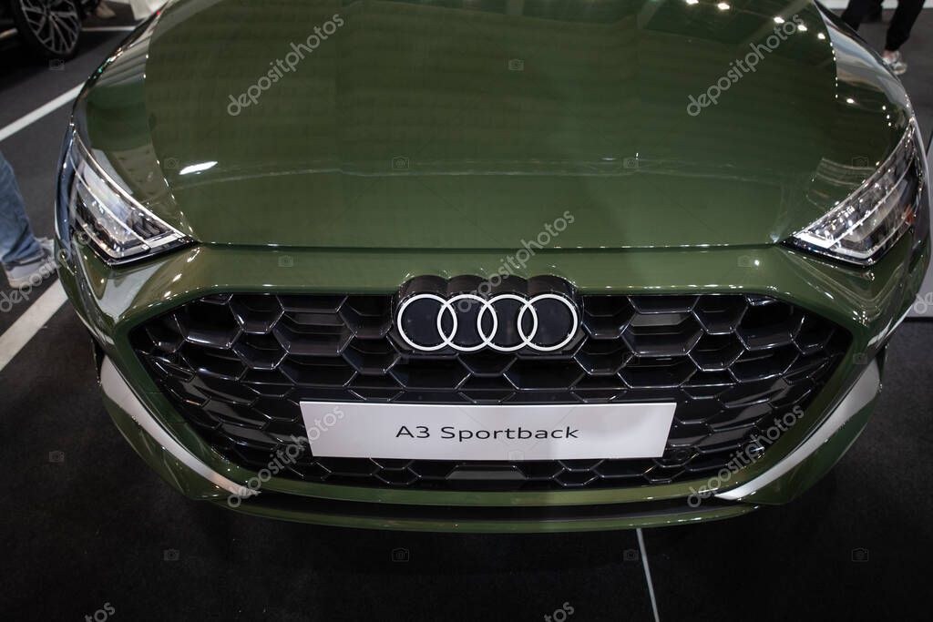 BELGRADE, SERBIA - MARCH 15, 2025: The front grille of an Audi A3 Sportback in a Belgrade showroom features the chrome Audi rings and model badge against a green paint finish, capturing the luxury brand's design signature.