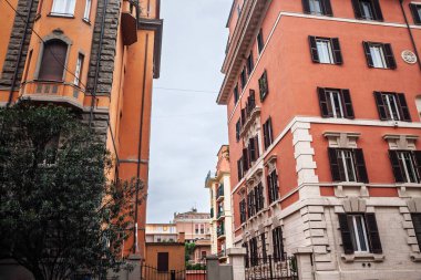 Prati, orta Roma, İtalya 'da klasik 20. yüzyıl başları apartman blokları, turuncu ve terracotta ön cepheleri, taş temizleme ve koyu ahşap panjurlar bulutlu bir günde dar bir ara sokağı çerçeveler..