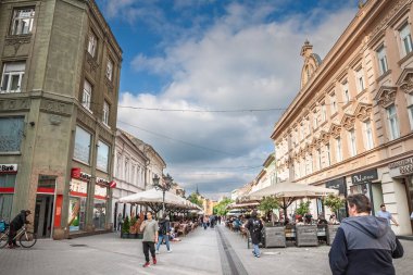 NOVI SAD, SERBIA - 16 Haziran 2025: Sırbistan 'ın Novi Sad kentindeki Zmaj Jovina Caddesi, kafeler, şemsiyeler ve yaya bölgesi boyunca uzanan tarihi cephelerle. Novi Sad 'ın ana yaya caddesi..