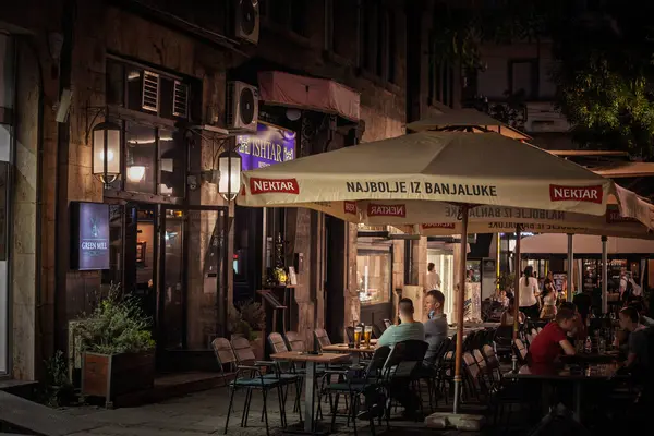 BELGRAD, SERBIA - 16 Haziran 2025: Nektar Pivo gece Belgrad 'da bir bar terasında şemsiyeleri markalaştırdı. Bu, Banja Luka 'daki Banjalucka Pivara bira fabrikasında üretilen Bosna biralarından biri..