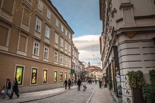 LJUBLJANA, SLOVENIA - 17 Aralık 2024: Ljubljana 'daki Wolfova Ulica' daki yayalar, Slovenya şehir merkezinde Habsburg döneminden kalma mimariyi gözler önüne seren cepheleri ve vitrinleri restore ettiler.