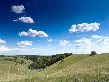 Sırbistan 'ın Voyvodina kentindeki Banat kentindeki Zagajicka Brda' nın yuvarlanan çimenli tepeleri, dağınık bulutlarla dolu mavi bir gökyüzünün altında. Sırp doğasının bir sembolü..