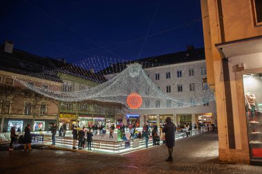 VILLACH, AUSTRIA - 28 Aralık 2024: Villach, Avusturya 'daki buz pateni pistinin gece görüşü, noel ışıklarının altında. Aileler şehir merkezinde kayıyorlar, tatil sezonunu yansıtıyorlar..