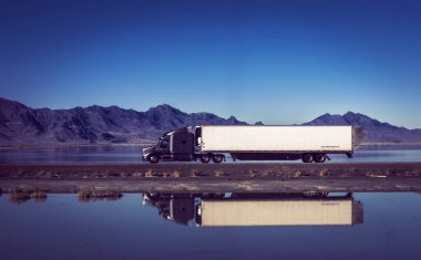 The semi truck confronts the dangers of the winding, high voltage western road, surrounded by raw power and natural beauty