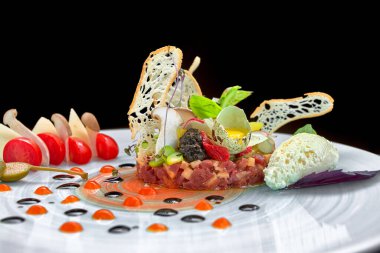 Kuşkonmaz ve domatesli sığır eti tartar, koyu bir arka planda.