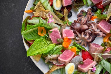 Deniz mahsullü salata, ton balığı ve tabakta ahtapot, koyu beton.