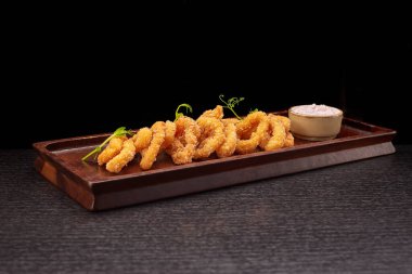 Ahtapot yüzükleri ahşap bir tahtanın üzerinde sos ile birlikte.