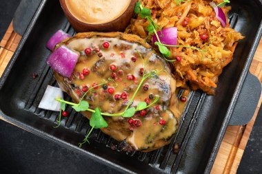 Soslu biftek ve haşlanmış lahana, tavada, ahşap arka planda.