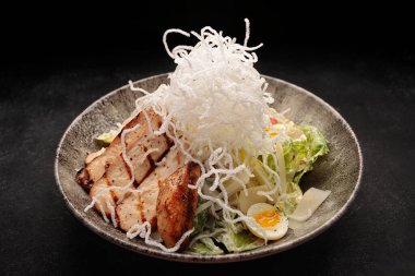 Koyu betondan yapılmış tavuk peynirli ve otlu Sezar salatası.