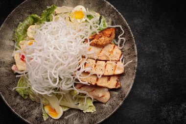 Koyu betondan yapılmış tavuk peynirli ve otlu Sezar salatası.