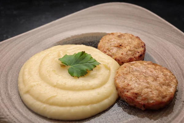 Steamed meat cutlets with boiled mashed potatoes, on dark concrete