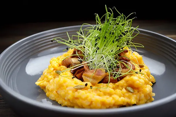 stock image Risotto with mushrooms, pumpkin and herbs on a dark background