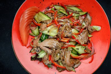 Kırmızı tabakta dana eti, sebze ve sos ile sıcak salata.