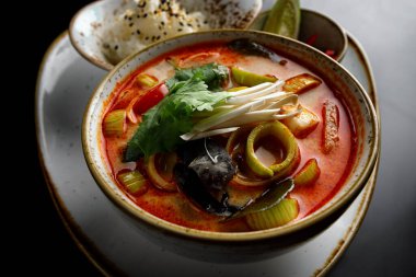 Tom Yum çorbası, karides, midye ve mürekkep balığı, siyah arka planda.