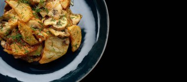 Siyah bir arka planda, tabakta mantarlı kızarmış patates.