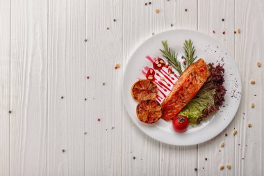 Beyaz ahşap arka planda, limonlu ve otlu kızarmış alabalık.