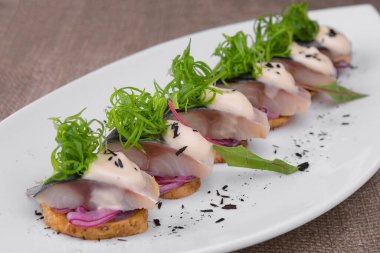 Soğan ve patatesle dilimlenmiş tuzlanmış uskumru tabakta.