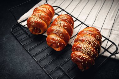 Izgarada hamur içinde pişmiş sosis, koyu bir arka plan.