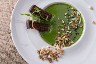 Kremalı ıspanak çorbası, kızarmış ekmek, beyaz tabakta, çuval bezinde.