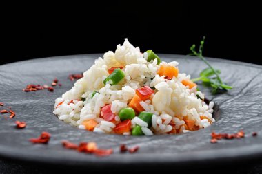 Siyah arka planda sebzeli risotto, siyah tabakta.