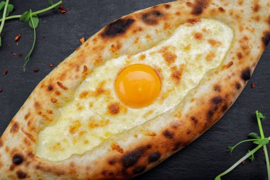 Siyah taşın üzerinde yumurta ve peynirli Adjarian Khachapuri.