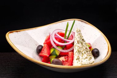 Siyah arka planda peynirli ve sebzeli Yunan salatası