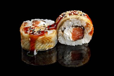Sushi roll Philadelphia special, with eel, salmon and cream cheese, on a black mirror