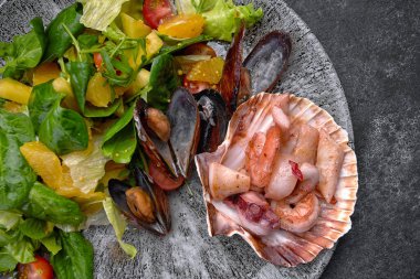 Seafood cocktail on a plate with herbs and tomatoes, on gray concrete