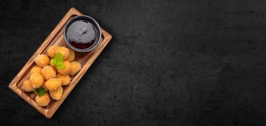 Cheese nuggets with fruit jam, on a wooden board, on a gray background