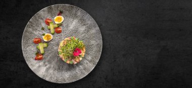 Olivier salad on a plate with vegetables, on a gray concrete background