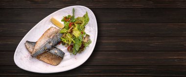 Baked mackerel fillet with salad and mushrooms, on a plate, on a wooden background. Banner