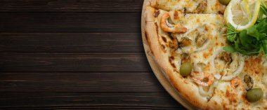 Marinara pizza with squid mussels shrimp olives and lemon, on a wooden background. Banner
