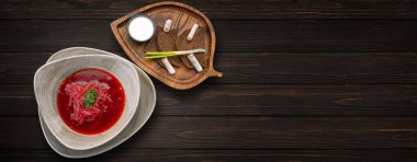Ukrainian borscht with lard, green onions and sour cream, on a wooden background. Banner