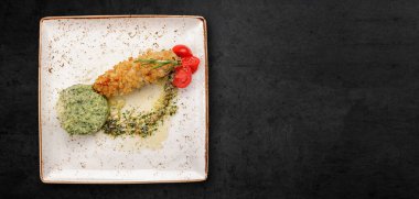 Kyiv style cutlet, in a plate, on a dark concrete background. Banner