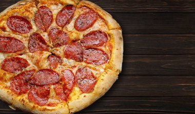 baked pizza with sausage, cheese and spices, on a wooden board