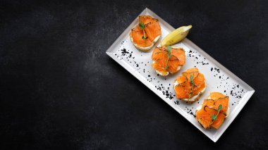 Bruschetta with salmon and butter, on dark concrete. Banner